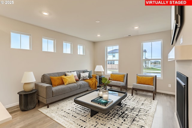 living room with a fireplace, light wood finished floors, recessed lighting, visible vents, and baseboards