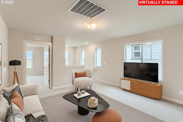 carpeted living area featuring baseboards, visible vents, and a textured ceiling