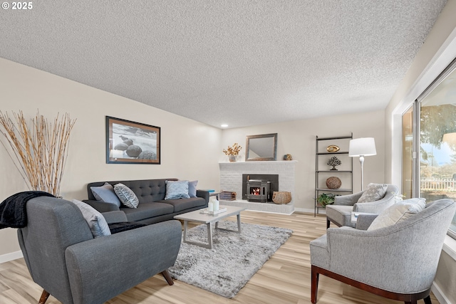 living room with a brick fireplace, light hardwood / wood-style flooring, and a textured ceiling