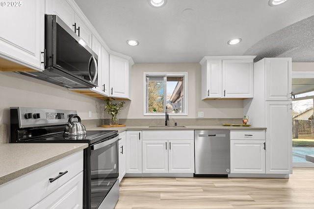 kitchen with white cabinetry, appliances with stainless steel finishes, light hardwood / wood-style floors, and sink