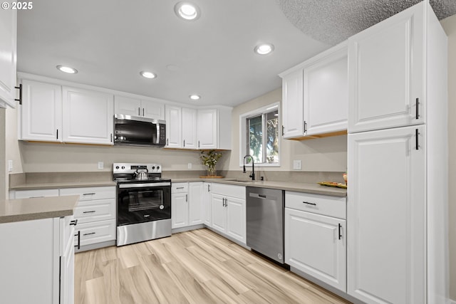 kitchen with white cabinetry, stainless steel appliances, light hardwood / wood-style floors, and sink