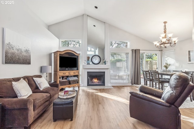 living room featuring light hardwood / wood-style flooring, high vaulted ceiling, and a chandelier