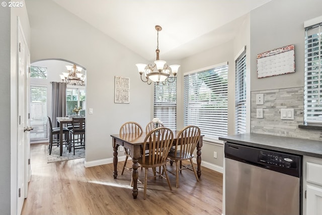 dining space featuring a chandelier, vaulted ceiling, and light wood-type flooring