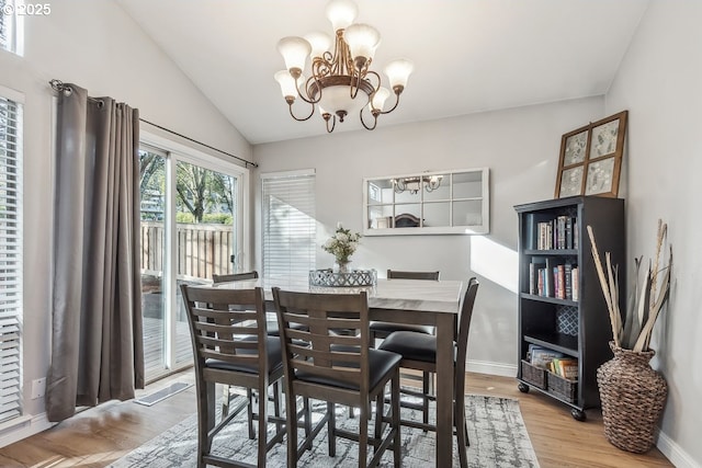 dining area featuring a notable chandelier, wood-type flooring, and vaulted ceiling