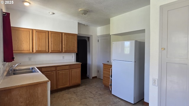 708 W Fourth Plain Blvd, Vancouver, WA 98660 - kitchen with a sink, a textured ceiling, freestanding refrigerator, brown cabinetry, and light countertops