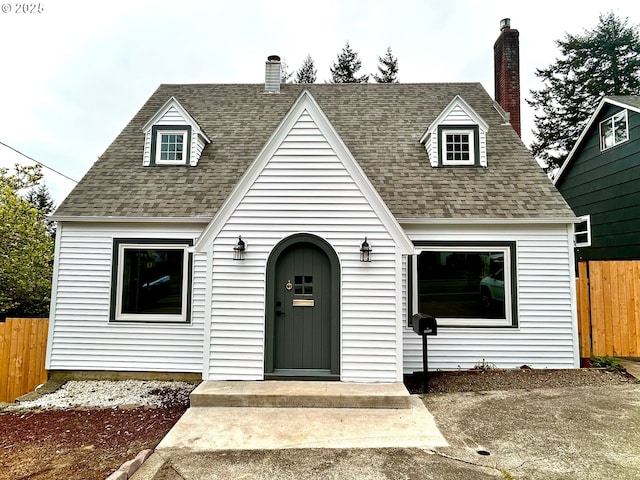 cape cod-style house with fence, a chimney, and roof with shingles