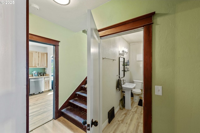 hallway with stairway, light wood-type flooring, a sink, and visible vents