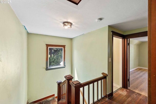 hall featuring baseboards, dark wood finished floors, and an upstairs landing