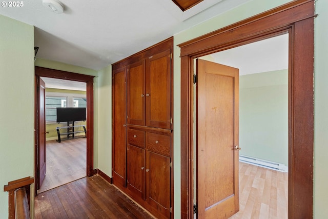 corridor featuring baseboards, wood finished floors, and baseboard heating