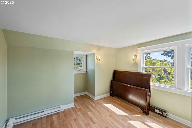 unfurnished room with baseboards, vaulted ceiling, baseboard heating, and light wood-style floors