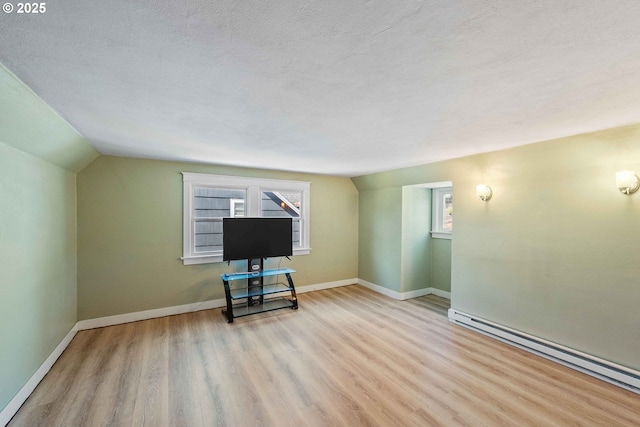 interior space featuring a textured ceiling, wood finished floors, baseboards, a baseboard heating unit, and lofted ceiling