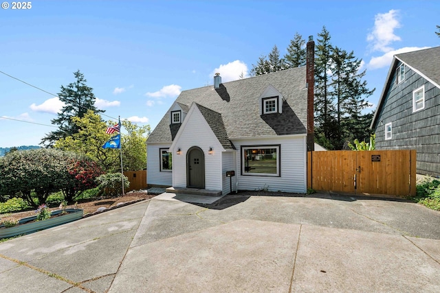 view of front of property featuring roof with shingles, fence, a gate, and a patio area