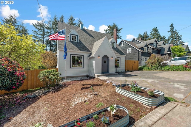 view of front of property with fence, a shingled roof, a garden, and a residential view