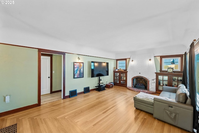 living area featuring baseboards, a fireplace, and visible vents