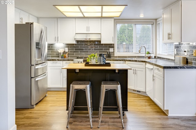 kitchen with white cabinets, a kitchen breakfast bar, and stainless steel fridge