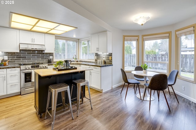 kitchen with white cabinets, a kitchen island, dark stone countertops, backsplash, and stainless steel range