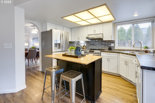 kitchen with wooden counters, sink, appliances with stainless steel finishes, white cabinetry, and a center island