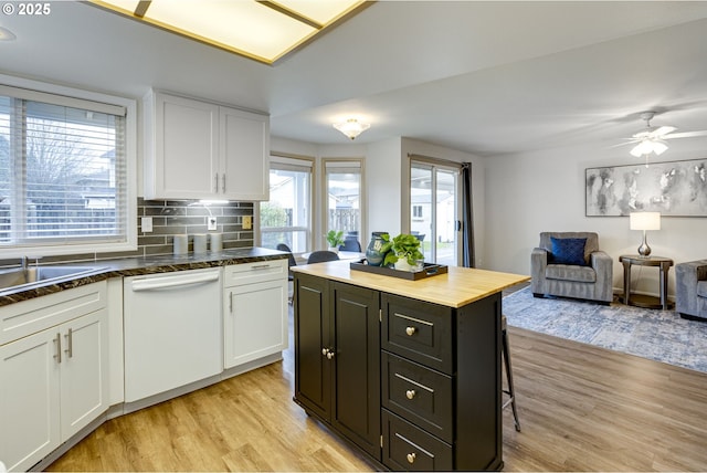 kitchen featuring white dishwasher, decorative backsplash, white cabinets, and a kitchen island