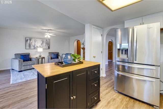 kitchen with stainless steel fridge with ice dispenser, a kitchen island, light hardwood / wood-style flooring, ceiling fan, and butcher block countertops