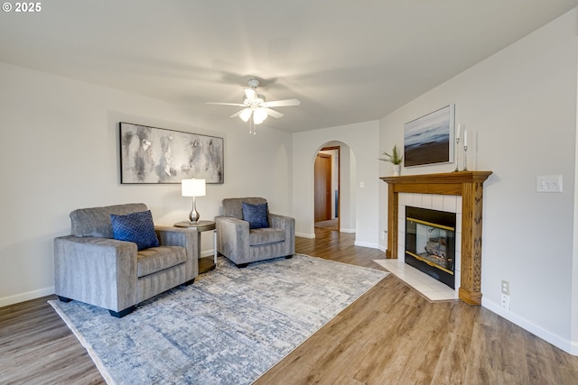 living room featuring hardwood / wood-style flooring, ceiling fan, and a fireplace