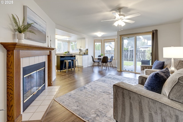 living room with ceiling fan, a wealth of natural light, light hardwood / wood-style flooring, and a fireplace