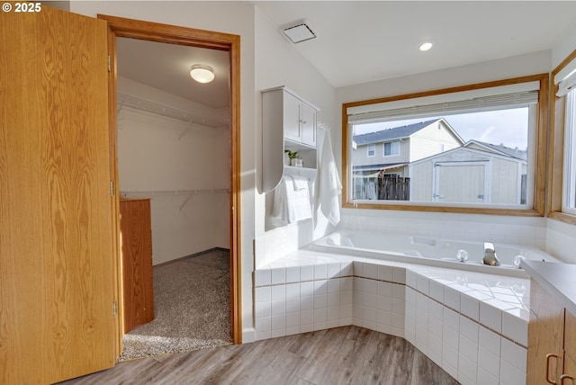 bathroom with hardwood / wood-style floors and a relaxing tiled tub