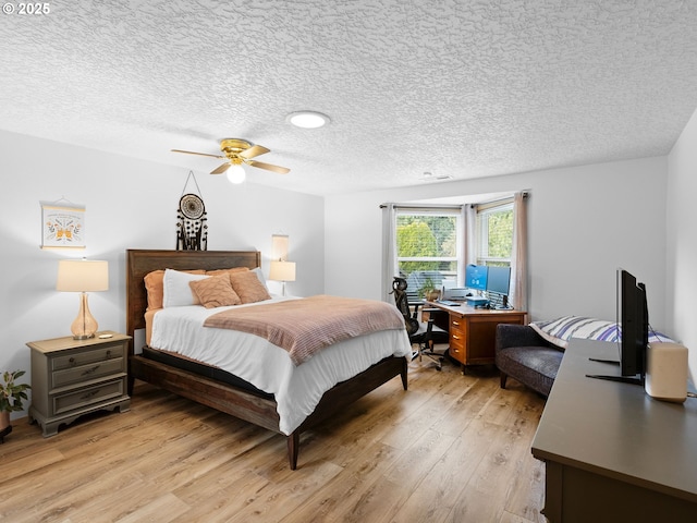 bedroom with a textured ceiling, light wood finished floors, and a ceiling fan