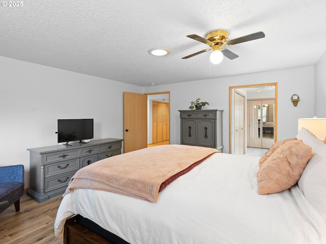 bedroom with light wood-style floors, a textured ceiling, and a ceiling fan