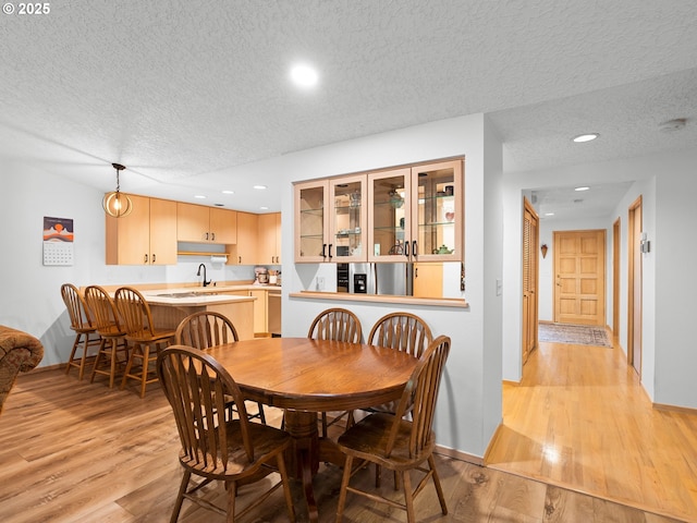 dining room with recessed lighting, baseboards, light wood-style flooring, and a textured ceiling