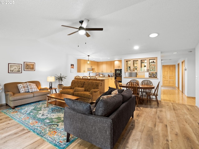 living room featuring light wood finished floors, lofted ceiling, recessed lighting, a ceiling fan, and a textured ceiling