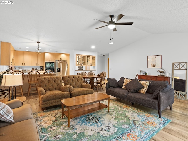 living area with recessed lighting, a ceiling fan, vaulted ceiling, a textured ceiling, and light wood-type flooring