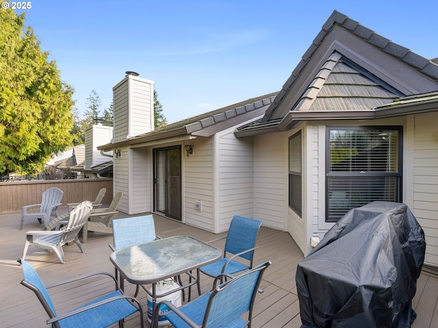 wooden deck featuring outdoor dining space, grilling area, and fence