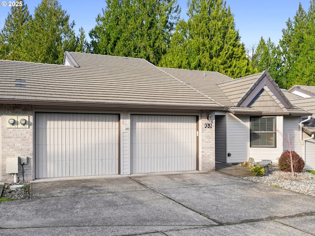 ranch-style home with a garage, concrete driveway, and brick siding