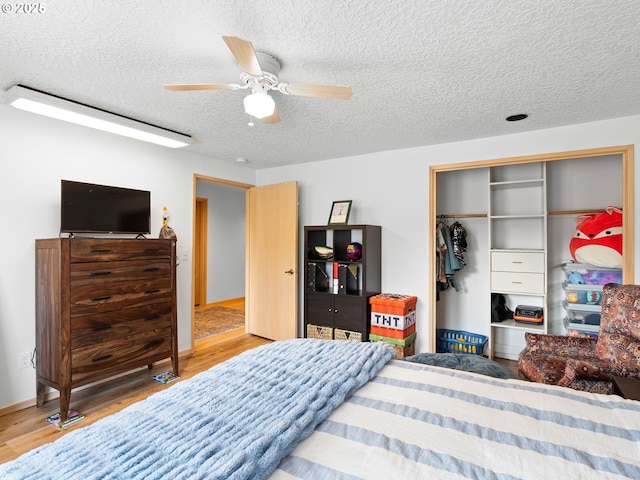 bedroom with a textured ceiling, ceiling fan, wood finished floors, baseboards, and a closet