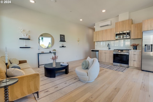 kitchen with stainless steel appliances, tasteful backsplash, light brown cabinetry, an AC wall unit, and light wood-type flooring