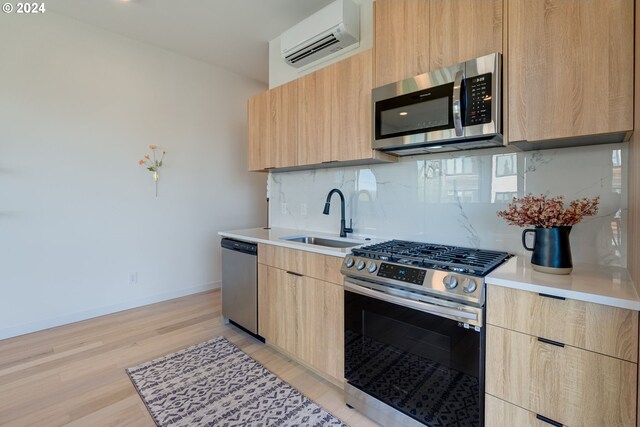 kitchen featuring light brown cabinetry, sink, an AC wall unit, appliances with stainless steel finishes, and backsplash