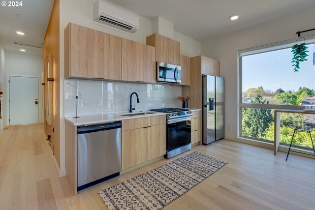 kitchen featuring sink, appliances with stainless steel finishes, tasteful backsplash, an AC wall unit, and light brown cabinets