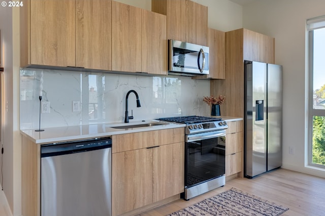 kitchen featuring sink, backsplash, light hardwood / wood-style floors, stainless steel appliances, and light brown cabinets