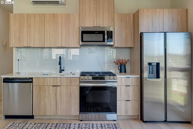 kitchen with a wall mounted AC, appliances with stainless steel finishes, light brown cabinetry, and sink