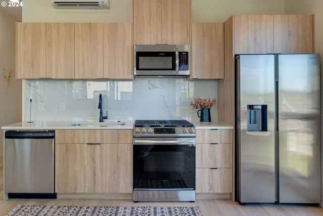 kitchen with sink, stainless steel appliances, a wall mounted AC, and light brown cabinets