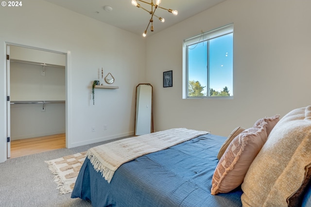 carpeted bedroom with a walk in closet and a notable chandelier