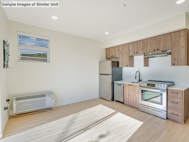 kitchen with a sink, stainless steel appliances, light wood-type flooring, under cabinet range hood, and a wall unit AC