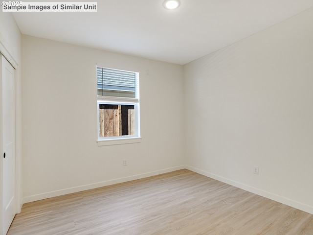 unfurnished bedroom with baseboards, light wood finished floors, and a closet