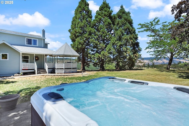 exterior space featuring a hot tub, a gazebo, a mountain view, and a lawn