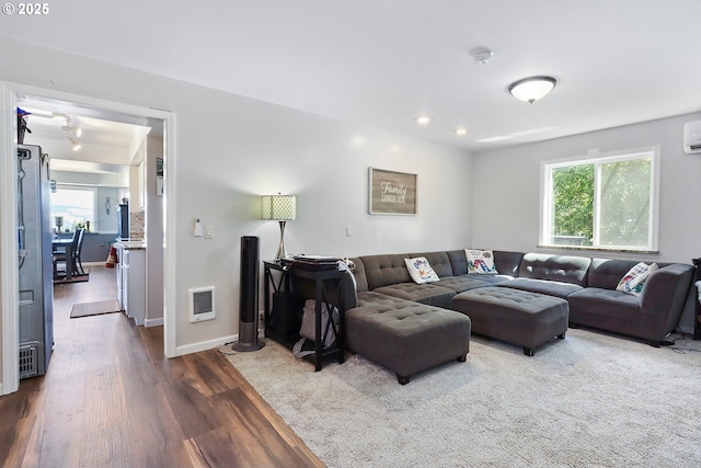 living room with plenty of natural light, dark hardwood / wood-style flooring, and a wall mounted AC