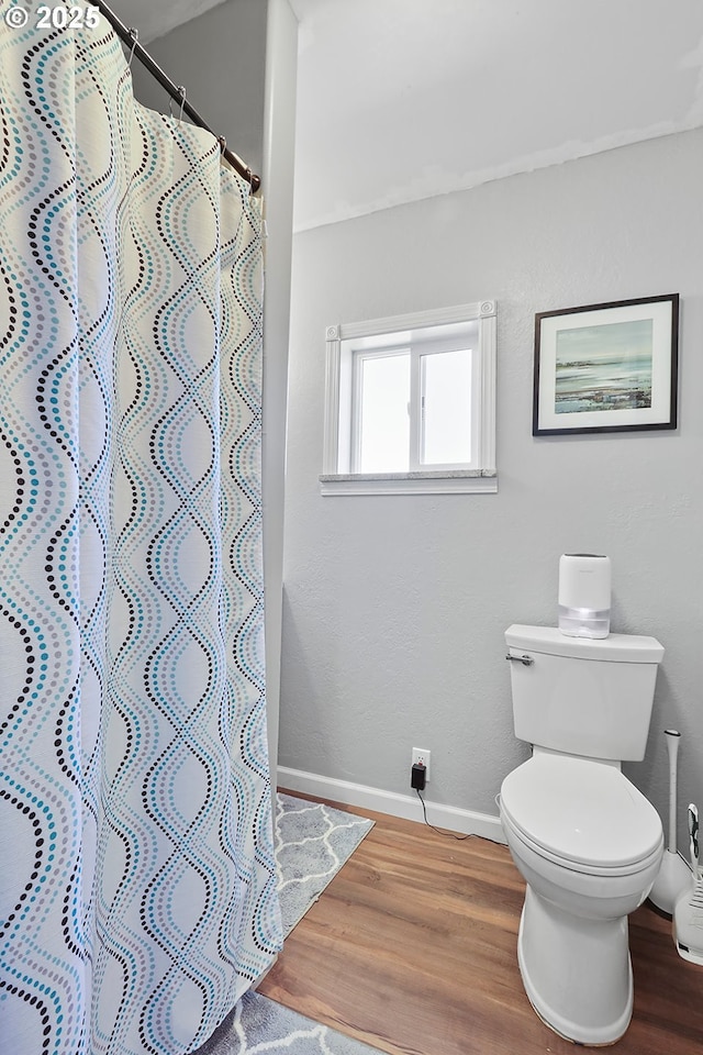 bathroom with hardwood / wood-style flooring, toilet, and a shower with shower curtain