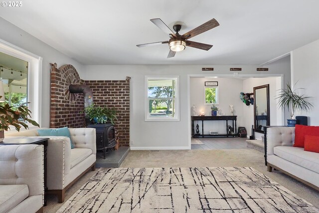 living room with light carpet, ceiling fan, and a wood stove