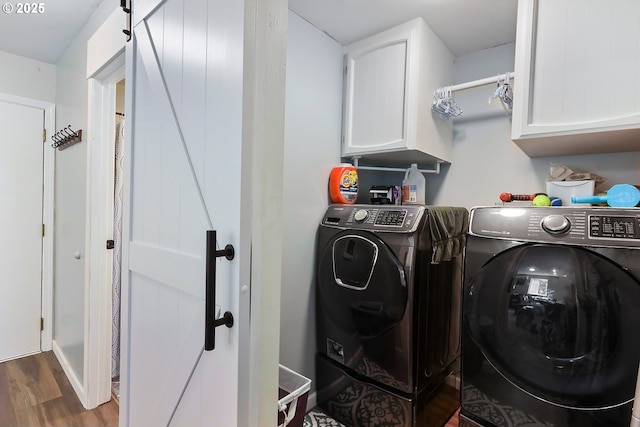 laundry area with hardwood / wood-style flooring, cabinets, a barn door, and washer and clothes dryer