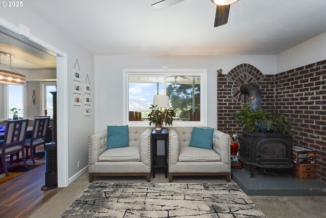 sitting room featuring a wood stove and ceiling fan