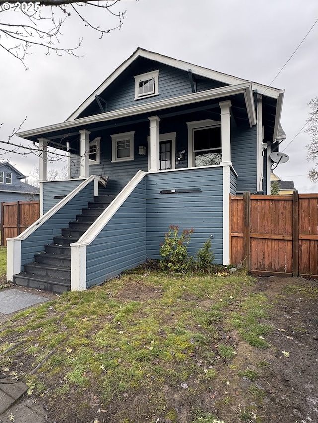 view of front facade with stairs, a front yard, and fence